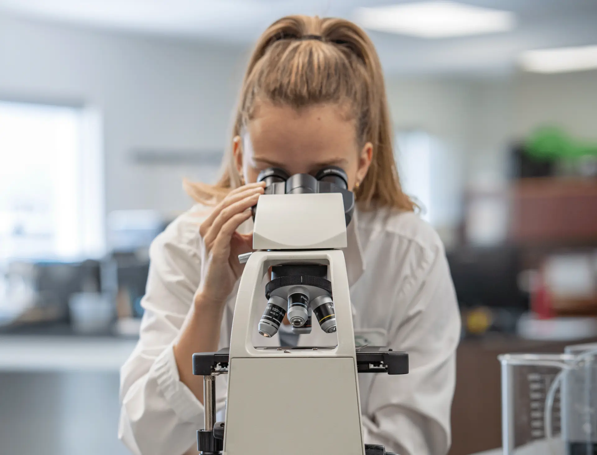 Kefiplant scientist examining samples through a microscope in the R&D lab