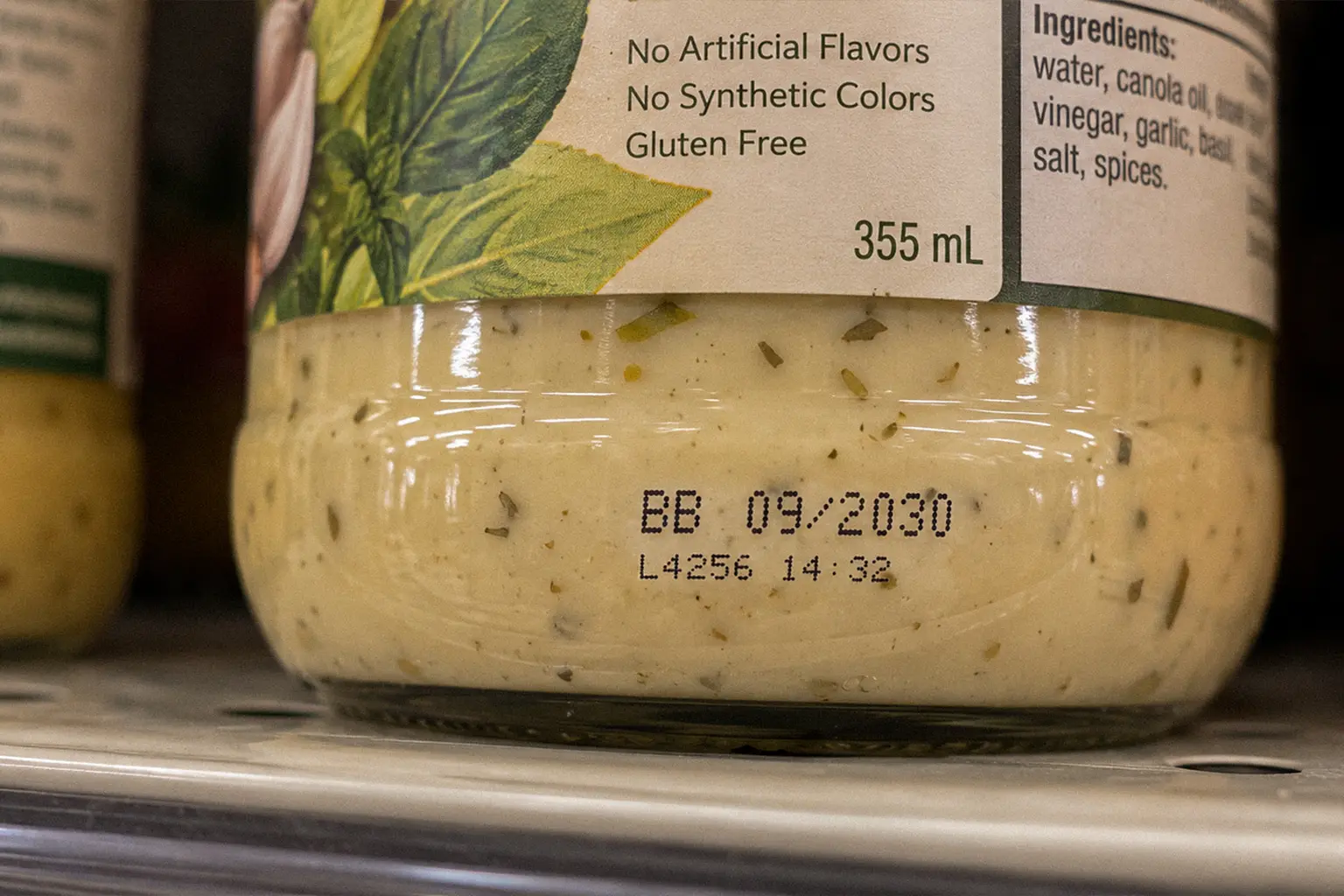 Close-up of a salad dressing jar on a store shelf showing its best-before date and clean ingredient list